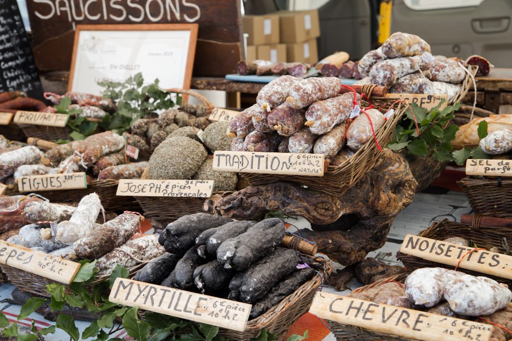 Stand sur un marché en plein air contenant de nombreuses variétés de saucisson